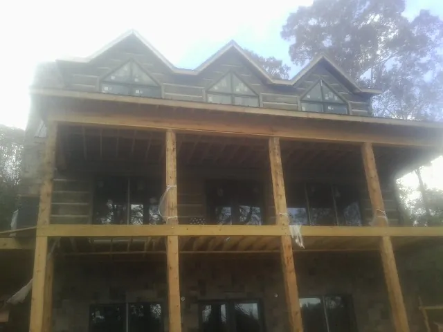 Dormers and porch framing on a large log home under construction — Roof Coating work by our crew in North Adams