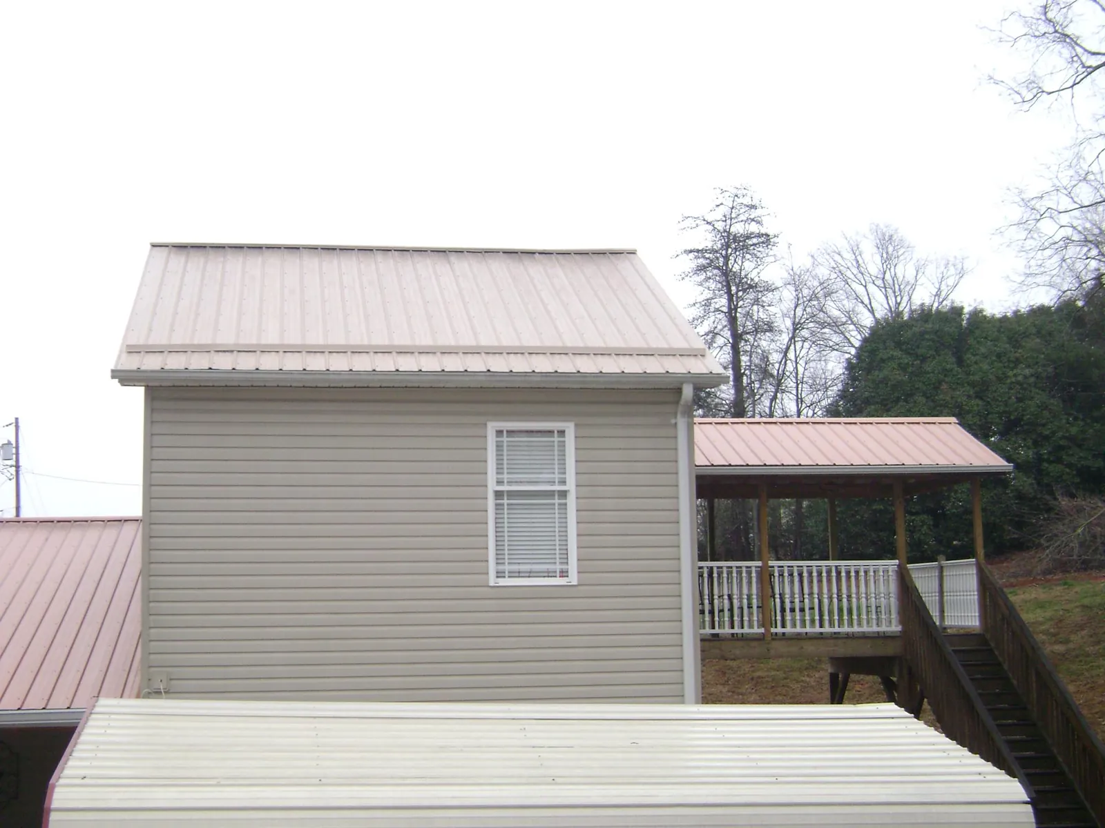 Tan metal roofs on a two story addition and attached porch, from a Roof Replacement job in North Adams